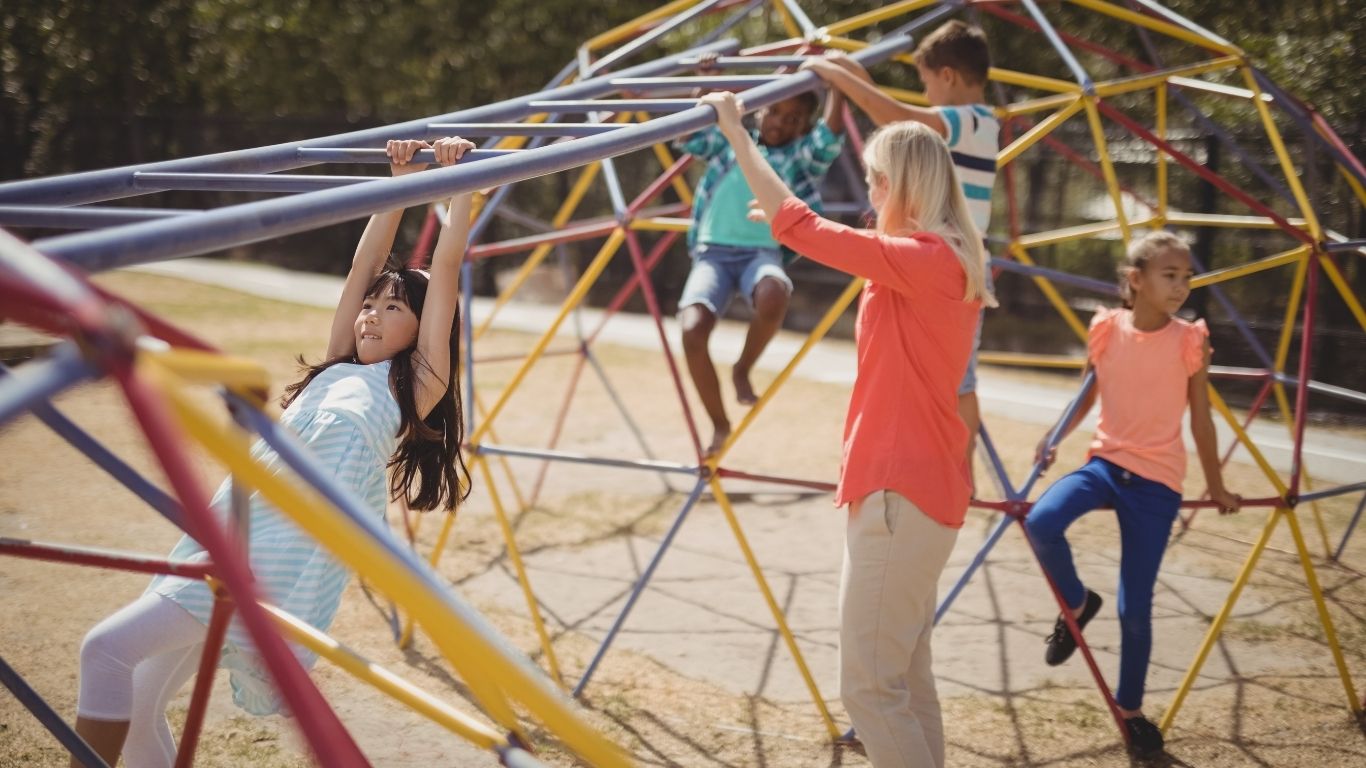 Children Playing On Playground In City Park Engaged In Football