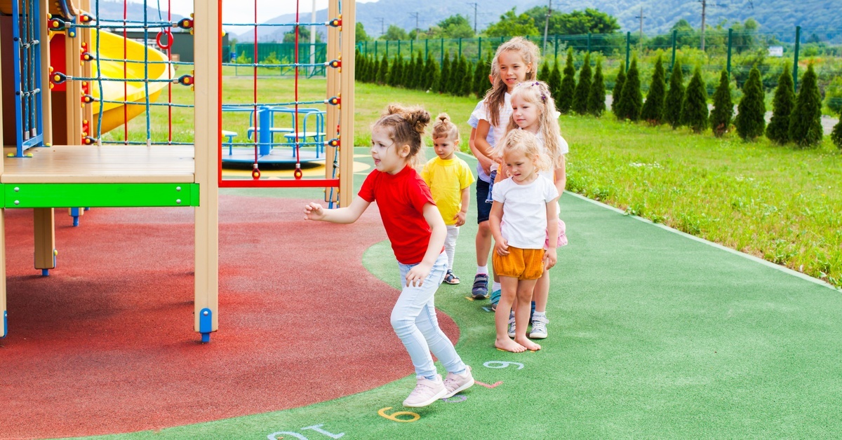 A group of young girls running and jumping on an outdoor playground. They're about to climb the platform. A group of young girls running and jumping on an outdoor playground. They're about to climb the platform.