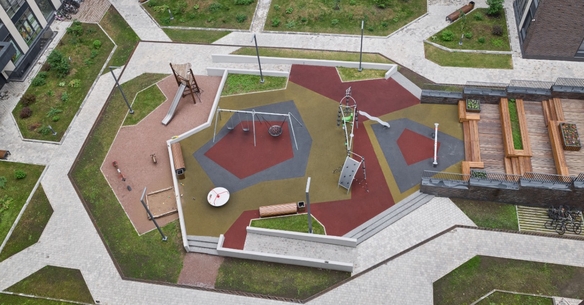 An aerial view of a playground with rubber safety surfacing, play structures, seating areas, and accessible pathways.
